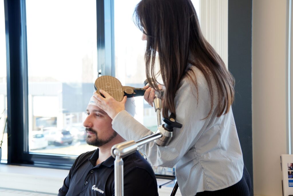 Clinician positioning a TMS treatment coil on a patient